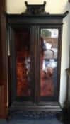 A good Oriental two door glazed cabinet with serpent top.