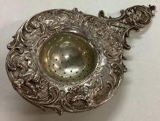A 19th Century German silver tea strainer embossed with cherubs.