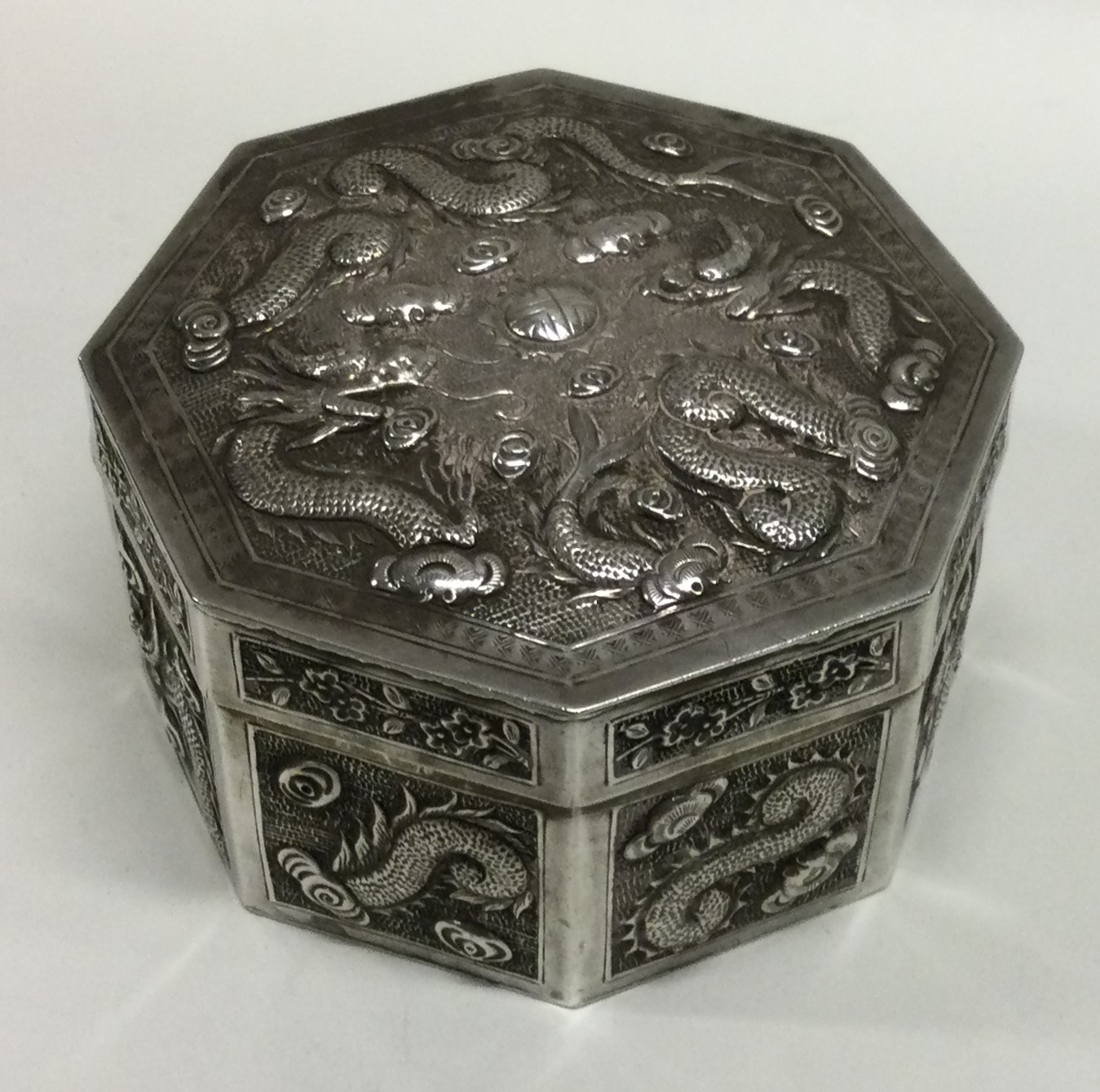 A 19th Century octagonal Chinese silver box embossed with dragons and flowers. - Image 2 of 3