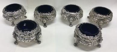 A fine set of six George III chased silver and glass salts embossed with flowers on figural feet.