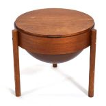 A 1960's Danish teak circular sewing table, the lift lid enclosing a swivel 'basket', on three