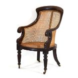 A 19th century mahogany and bergere armchair with scrolled arms, turned front legs and castors