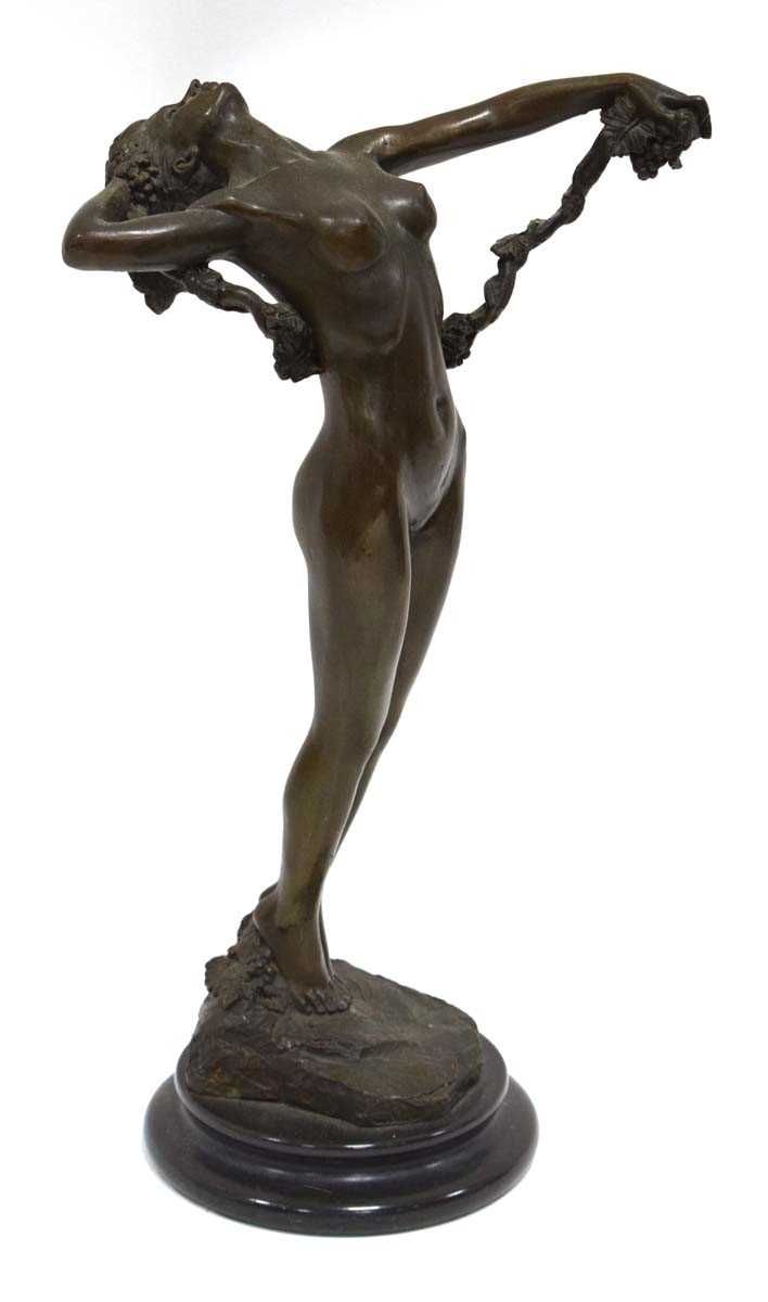 A bronze figure in the Art Deco manner modelled as a nude female standing on a rock holding vines,