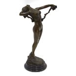 A bronze figure in the Art Deco manner modelled as a nude female standing on a rock holding vines,