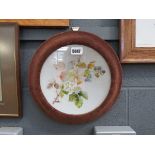 An opaline glass charger, hand decorated with floral sprays, mounted in a wall-hung frame, d. 36 cm