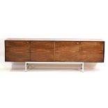 A 1970's rosewood four-door sideboard with rectangular moulded handles resting on an aluminium base,