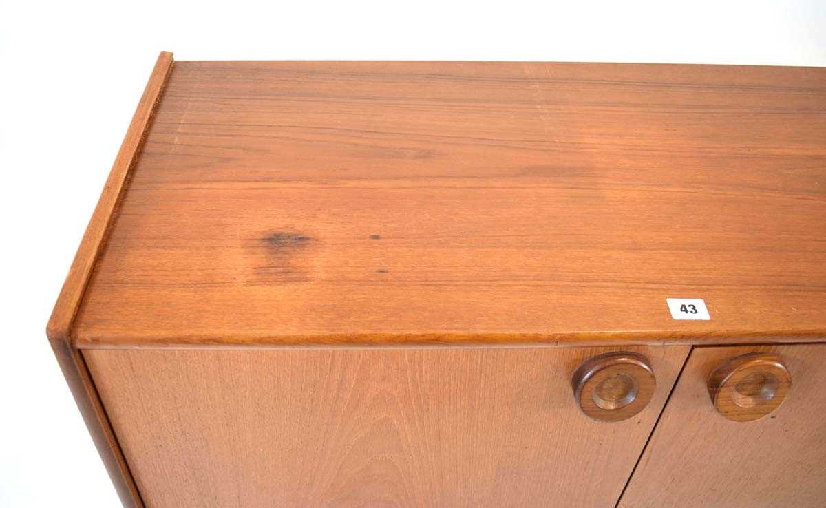 A 1970's and later teak cabinet, the two doors with circular moulded handles, on turned tapering - Image 4 of 4