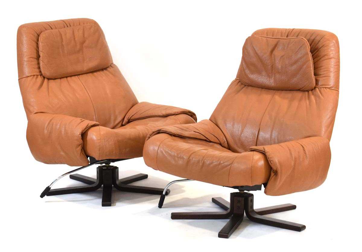 A pair of Swedish 1970's tan leather reclining armchairs on laminate five-star swivel bases*Sold