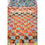 A large reversible specimen quilt rug decorated with pastel and psychedelic colours and patterns,