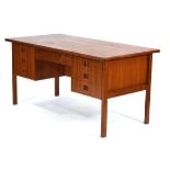 A 1960's Danish teak and crossbanded kneehole desk with an arrangement of seven drawers, the reverse