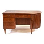 A 1950's Danish teak desk of swept serpentine form with a tambour cupboard and five drawers, gallery