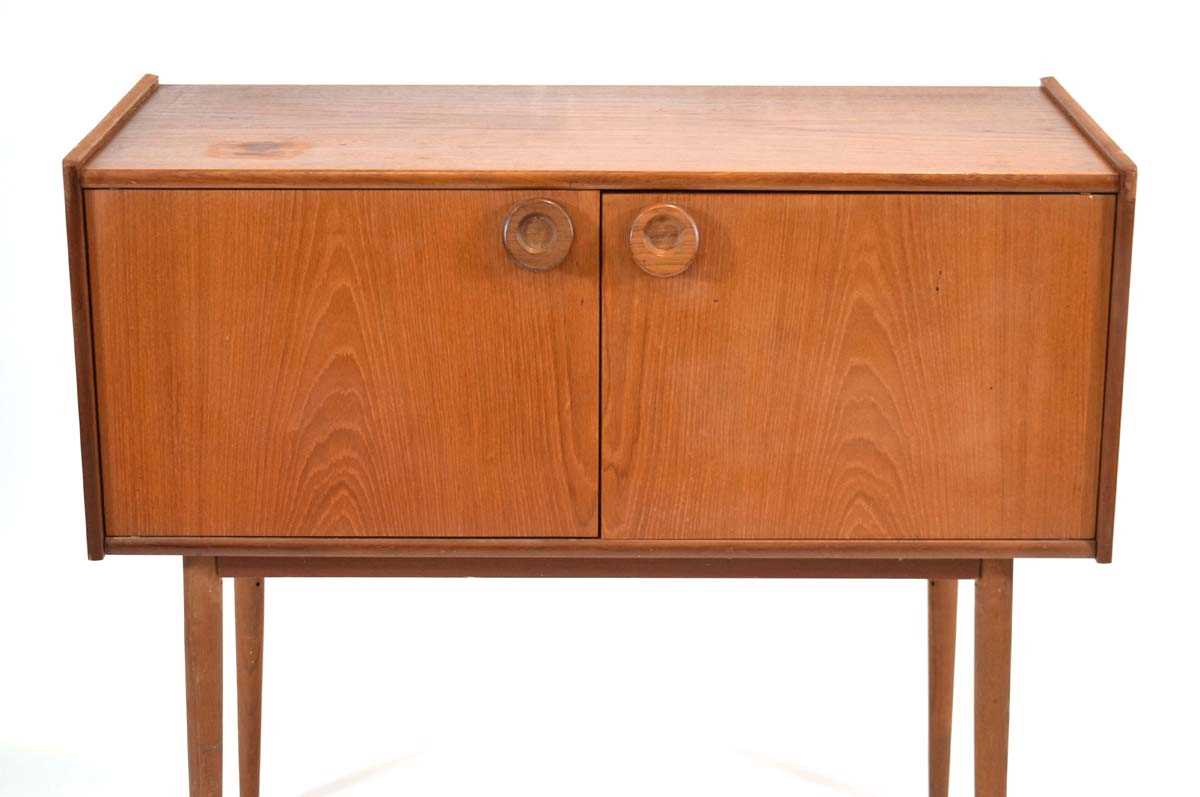 A 1970's and later teak cabinet, the two doors with circular moulded handles, on turned tapering - Image 2 of 4