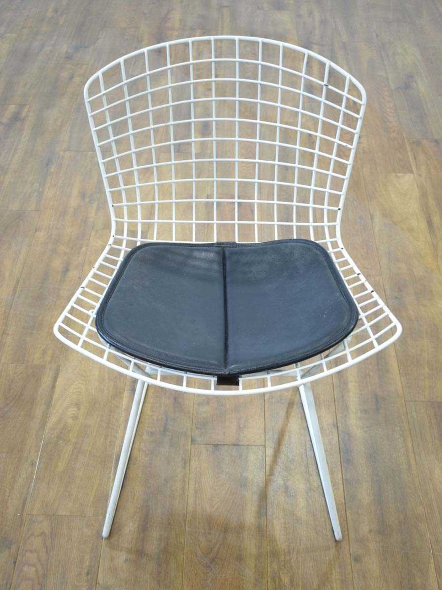 After Harry Bertoia, a 1960's 420-style side chair, enamelled in white, with a black padded seat *