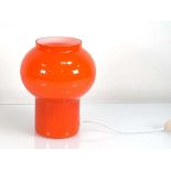 A glass table lamp with a moulded orange shade