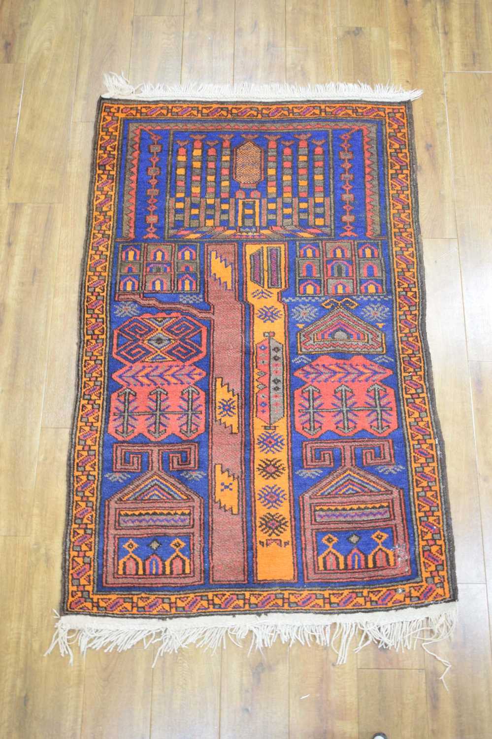 A mid-20th century woollen prayer rug, the blue ground with orange and red architectural motifs, 149