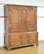 An 18th century oak armoire, the pair of panelled doors over an arrangement of three drawers on