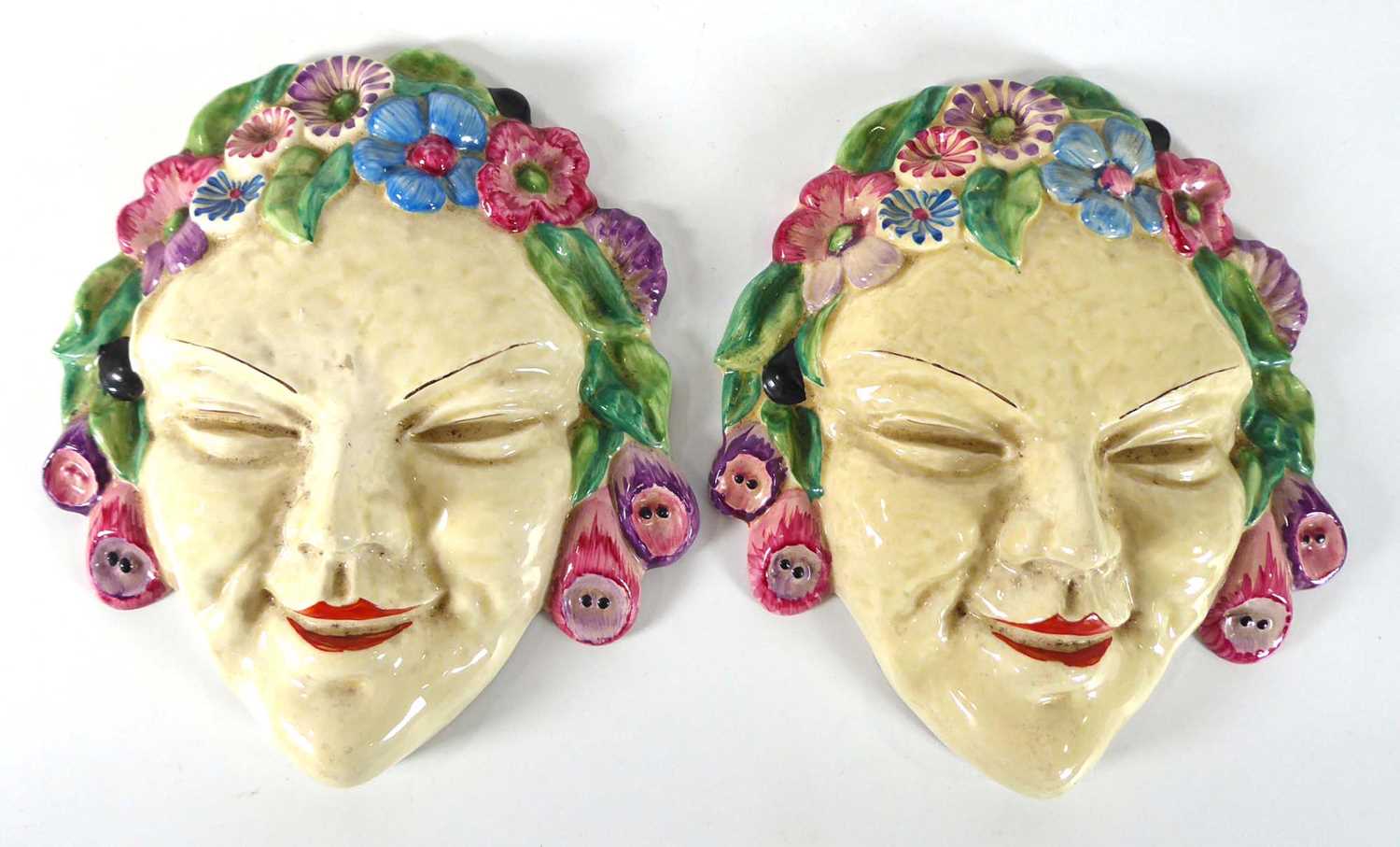 A pair of Clarice Cliff Bizarre wall masks, each depicting a female beauty wearing a floral