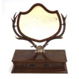 A late 19th century toilet mirror, the shield-shaped bevelled glass mirror supported by a pair of