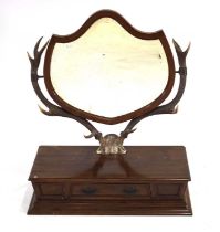 A late 19th century toilet mirror, the shield-shaped bevelled glass mirror supported by a pair of