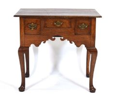 An 18th century oak lowboy or side table, the moulded surface over a shaped apron with three