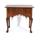 An 18th century oak lowboy or side table, the moulded surface over a shaped apron with three