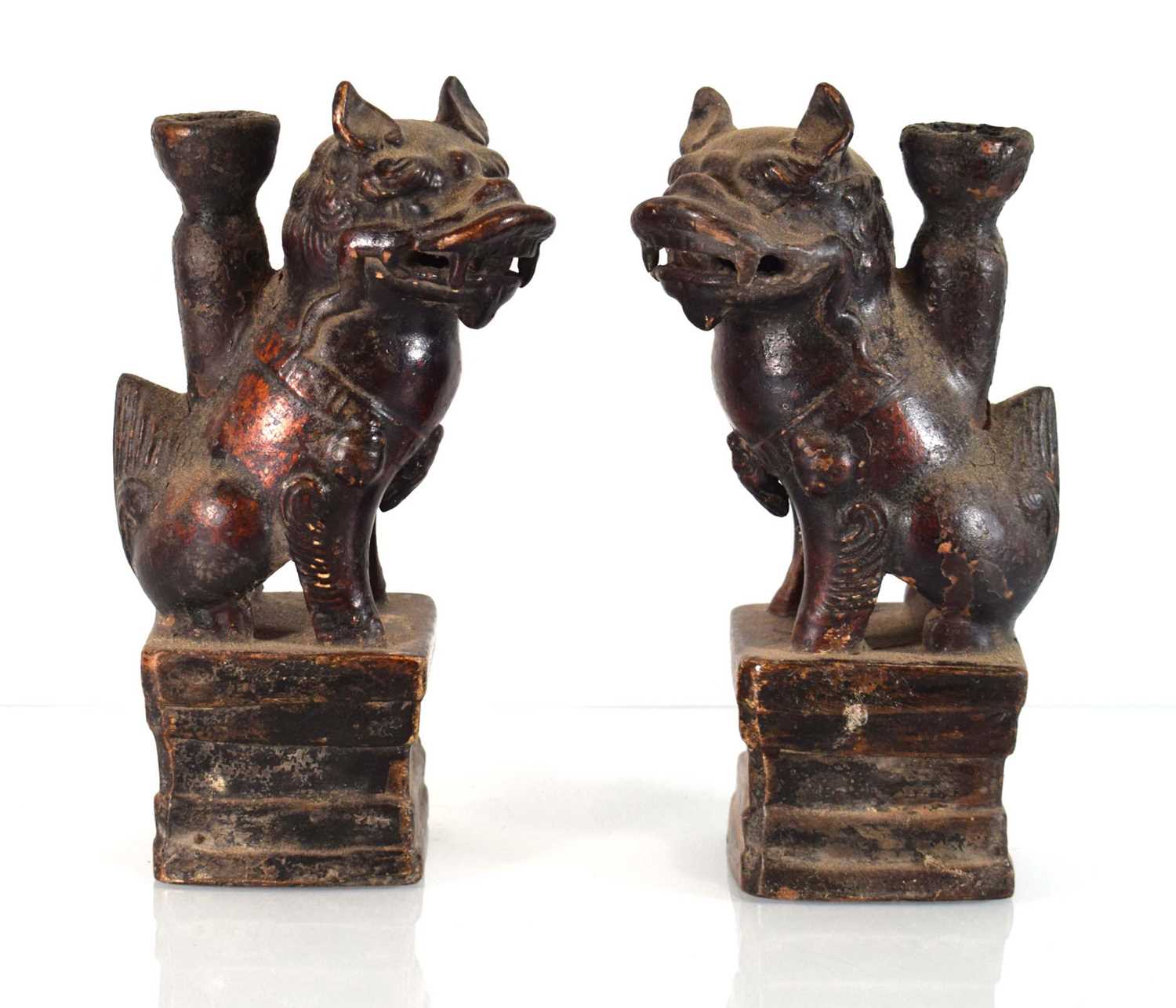 A pair of late 19th/early 20th century Chinese lacquered stoneware candlesticks modelled as foo