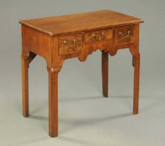 A Georgian walnut lowboy with moulded edges and three frieze drawers over a shaped apron, on