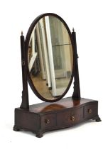 An early 19th century toilet mirror, the oval plate within a matching frame on a serpentine base