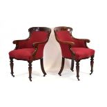 A pair of Victorian mahogany club carvers or armchairs upholstered in red with serpentine seats,