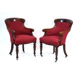 A pair of Victorian mahogany club carvers or armchairs upholstered in red with serpentine seats,