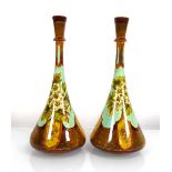 A pair of Doulton Lambeth bottle vases of slender form decorated with strawberry plants on a pale