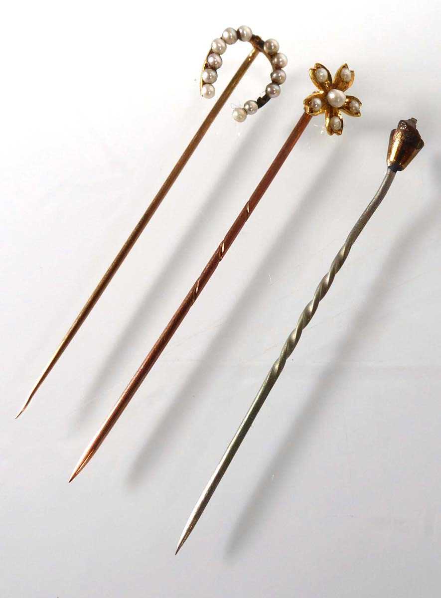 An 18ct yellow gold stick pin set seed pearls in a flowerhead setting, l. 5.8 cm, 1.2 gms and two