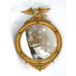 A 20th century giltwood wall mirror, the convex plate with a circular carved frame surmounted by a