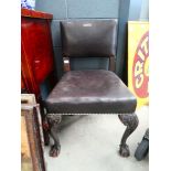 An 18th century style side chair with a carved oak frame, leather upholstery and ball and claw feet