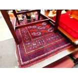 A Baluch(?) rug, the red ground with repeated Boteh symbols and matching bands, 181 x 106 cm