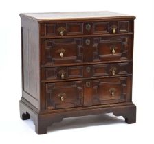 An 18th century oak panelled chest, the four drawers with geometric mouldings, on a later oak