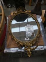 A 19th century giltwood and plaster wall mirror, the oval plate within a decorative frame surmounted