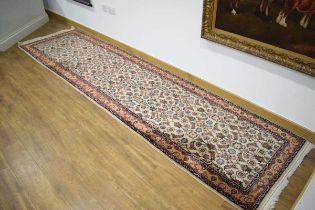 An Iranian carpet runner with a beige ground and red detail, 360 x 90 cm