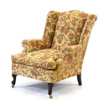 A 19th century and later upholstered open fireside armchair on scrolled feet with castors