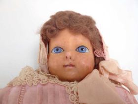 A 19th century wax headed doll with fixed blue glass eyes and wearing a pale pink dress, l. 54 cm (