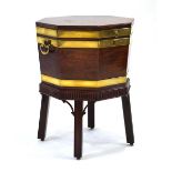 A George III mahogany and brass bound octagonal wine cooler with a lead lining, carved apron and