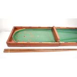 A Victorian table top bar billiards board, 122 x 36 cm, together with two associated cues