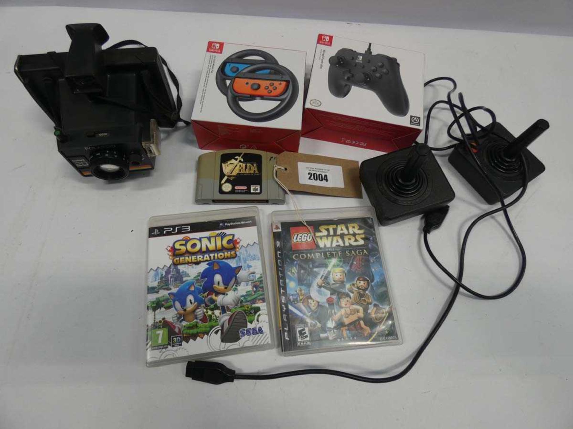 +VAT Switch controller accessories, N64 Zelda game, 2x PS3 games, 2x Atari joysticks and Polaroid