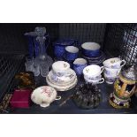 Cage containing a beer stein, decanter with shot glasses plus floral and blue and white crockery