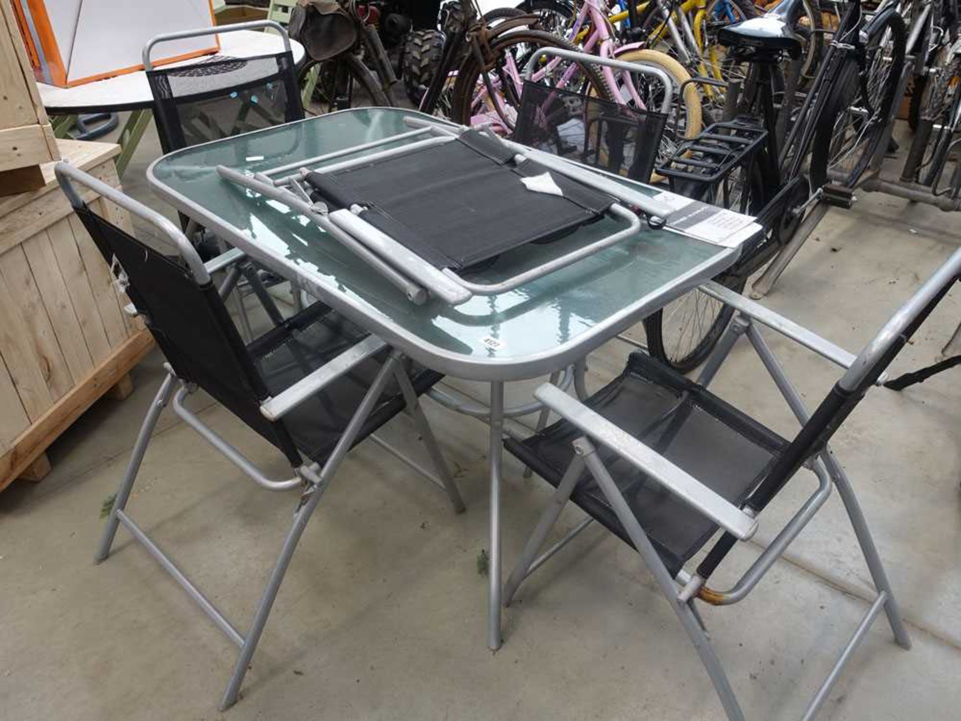 Silver rectangular metal glass topped garden table with four black chairs, in worn condition - Image 2 of 2