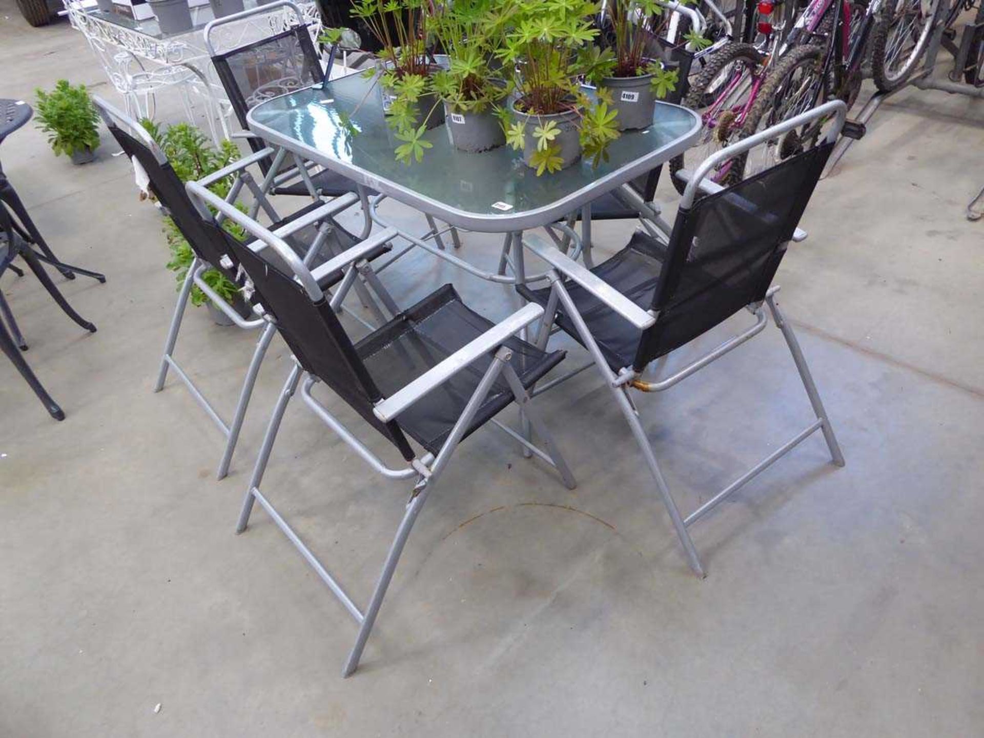 Silver rectangular metal glass topped garden table with four black chairs, in worn condition