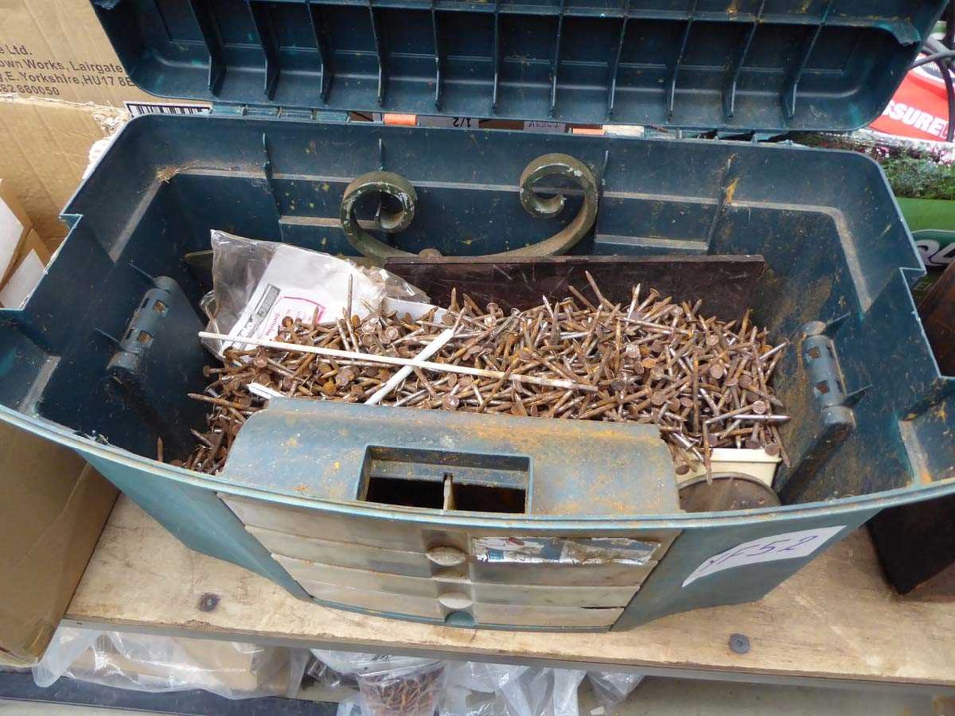 Green plastic toolbox containing a large quantity of nails