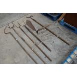 Assortment of ash-handled tools including hay cutter, pitchforks, shepherd's crook etc.