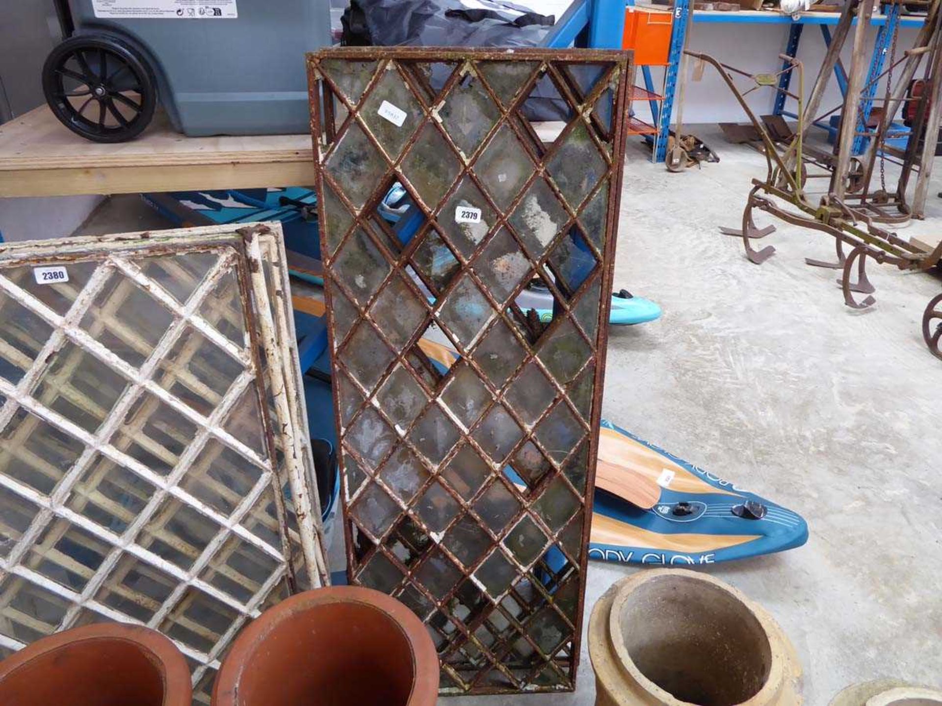 Pair of reclaimed windows with cast iron lattice framesLacking some glass