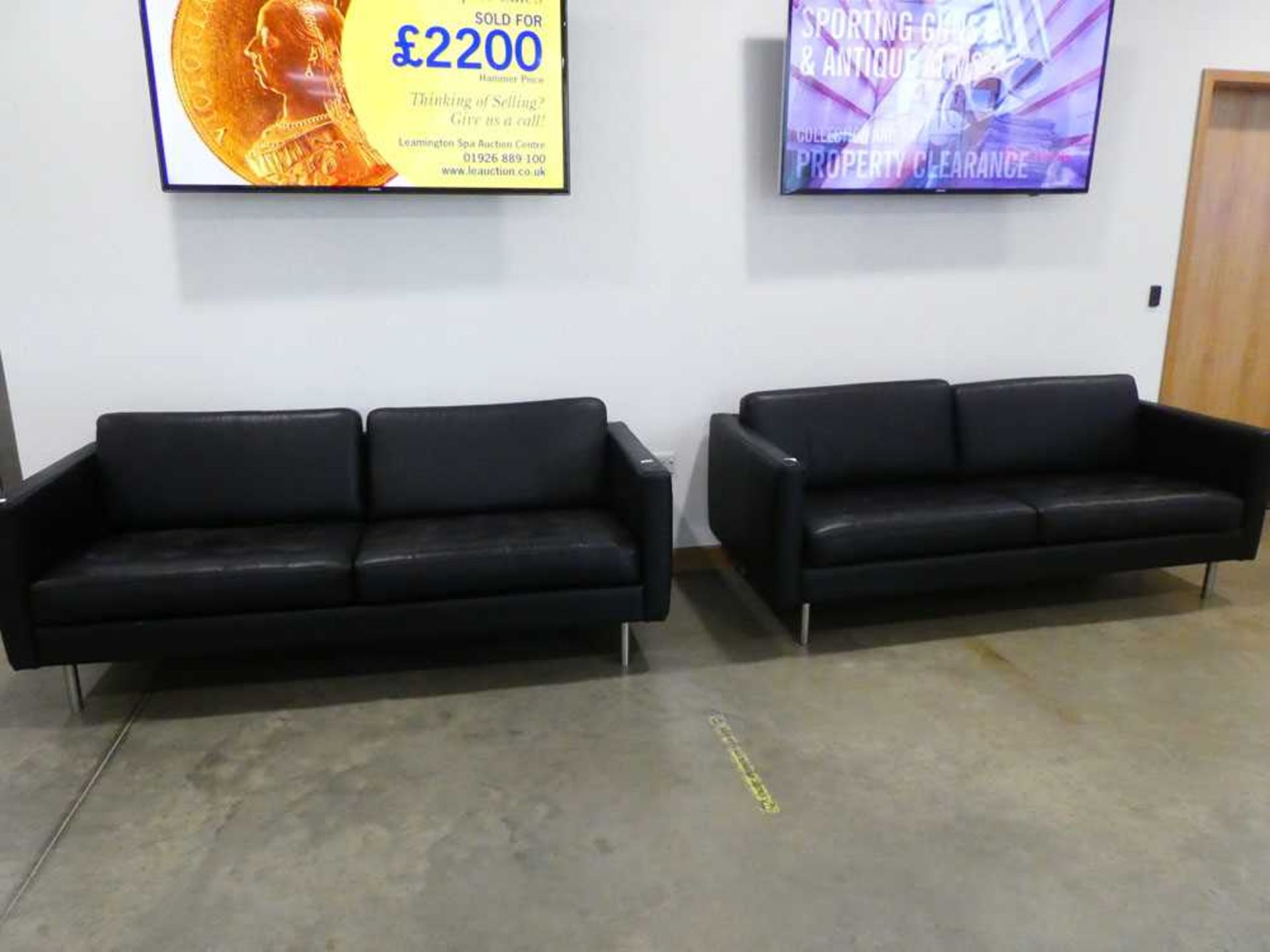 Pair of black leather effect three seater sofas